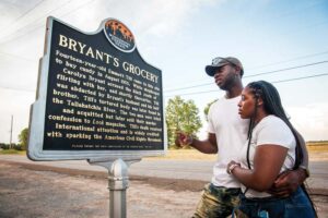 A couple reading the Mississippi Freedom Trail marker for Bryant's Grocery.